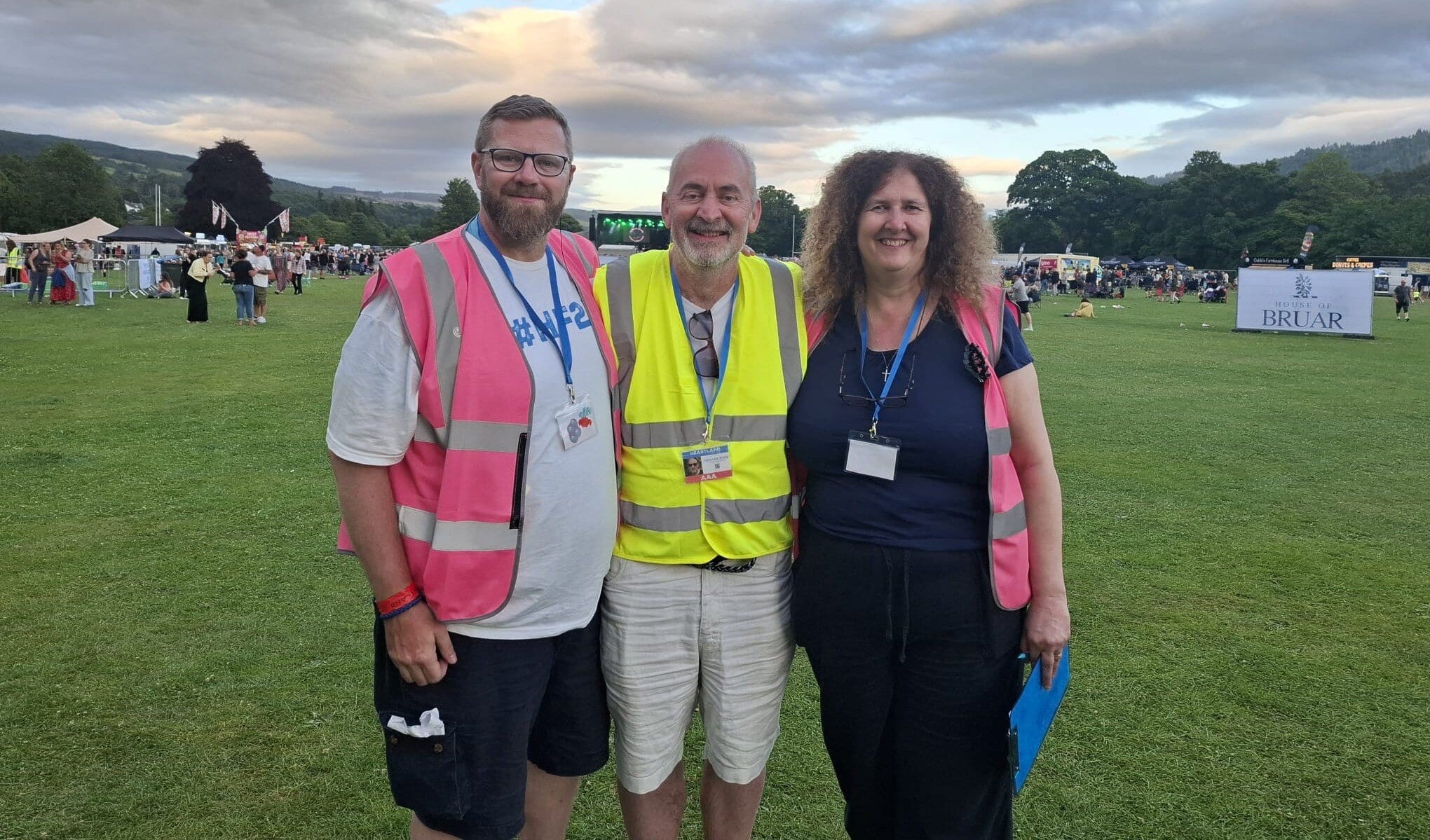 Crowd at Replay Festival with staff in safety vests enjoying outdoor music event.